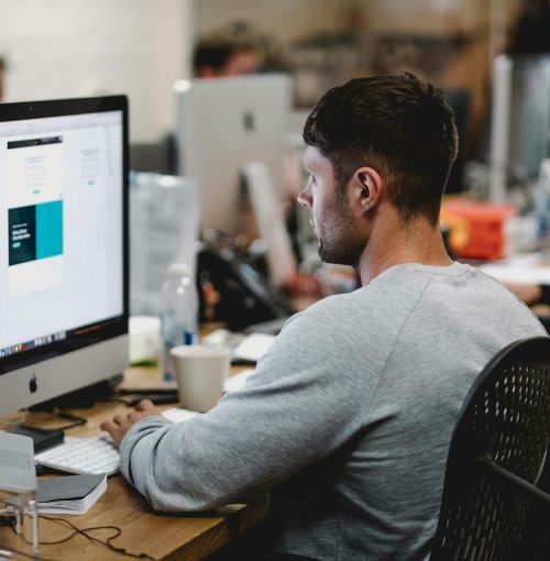 Photo by Studio Republic man in gray sweatshirt sitting on chair in front of iMac